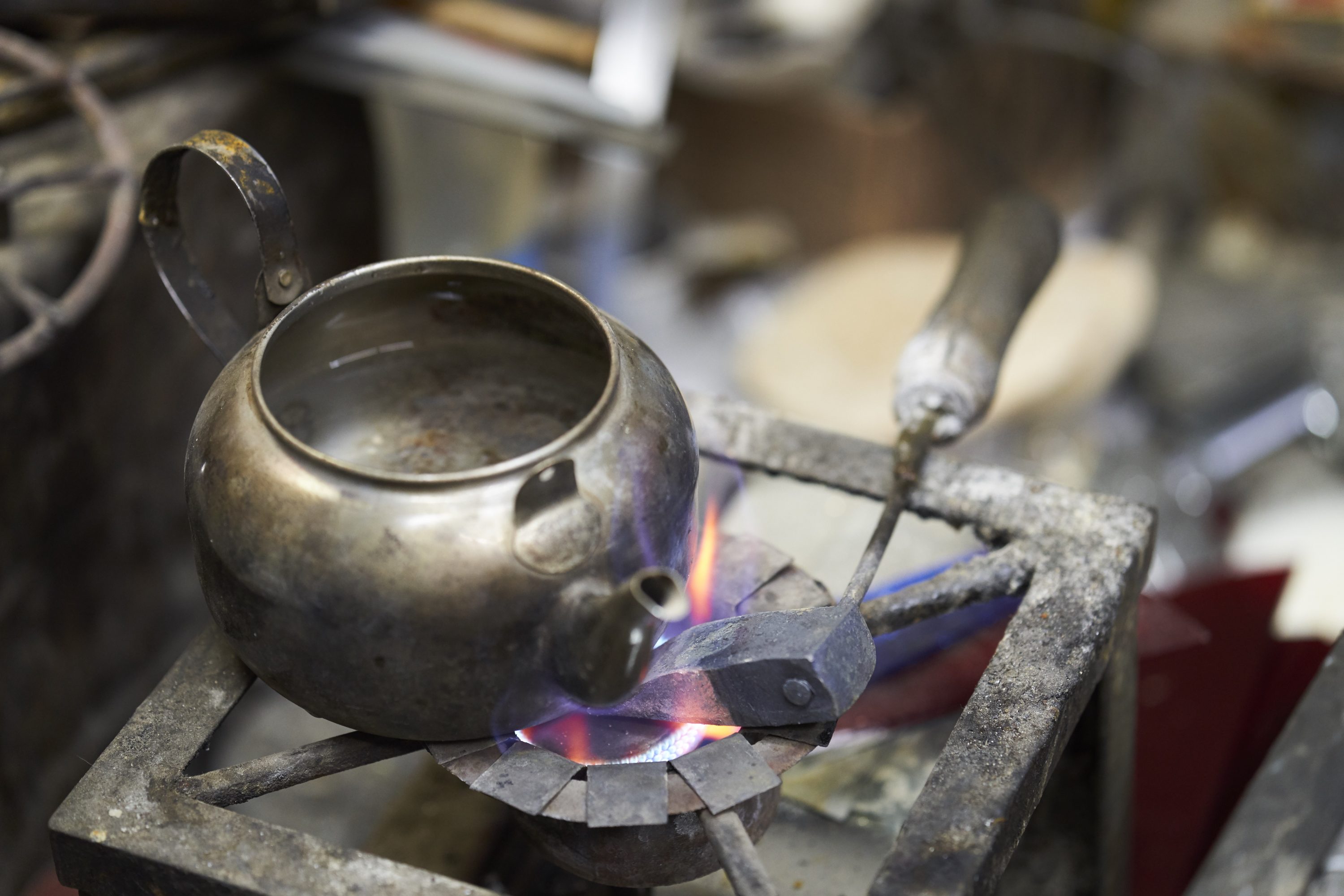 An artist heats his soldering tool and water for tea at the workshop of Atef Salama