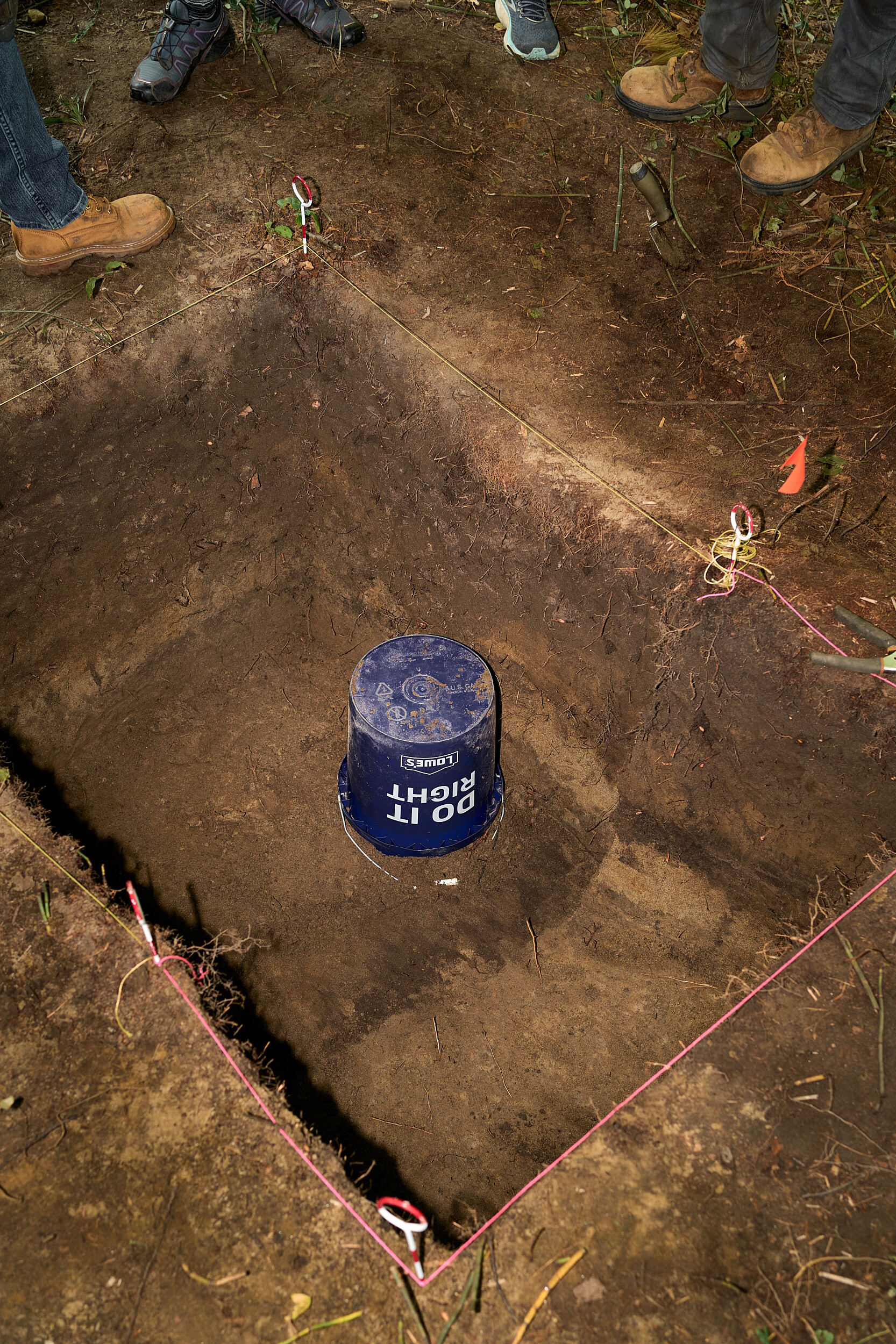 The dark dirt on the bottom and the wall of the hole are evidence of a hearth, and the light dirt is a compacted living floor.