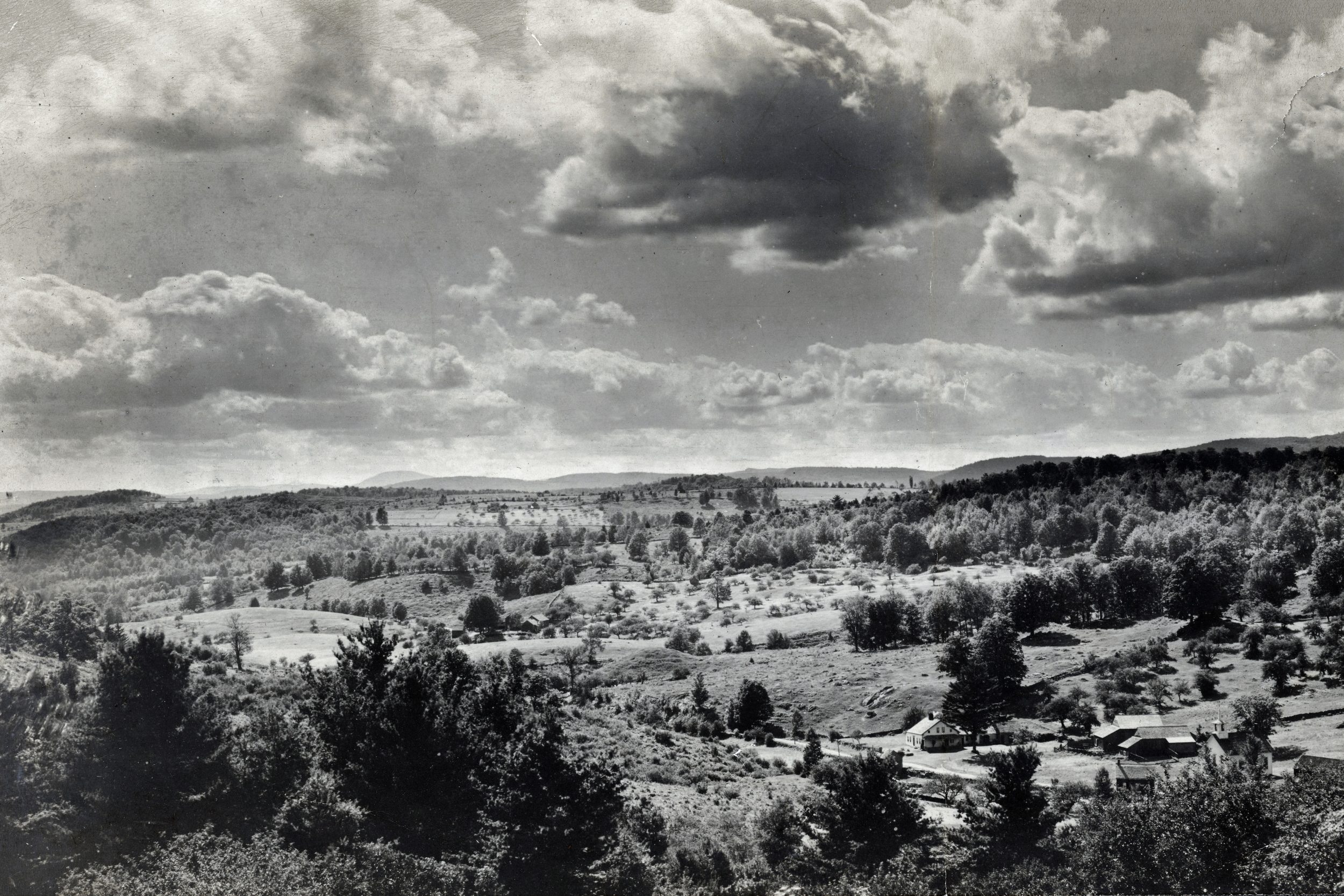 This photograph was taken from Kings Highway facing west around 1900 judging from the buildings that are in it. The most distant mountain that you can see towards the left hand side is Greylock. If you were to walk to these areas today you would be in deep woods. -Rowe Historical Society