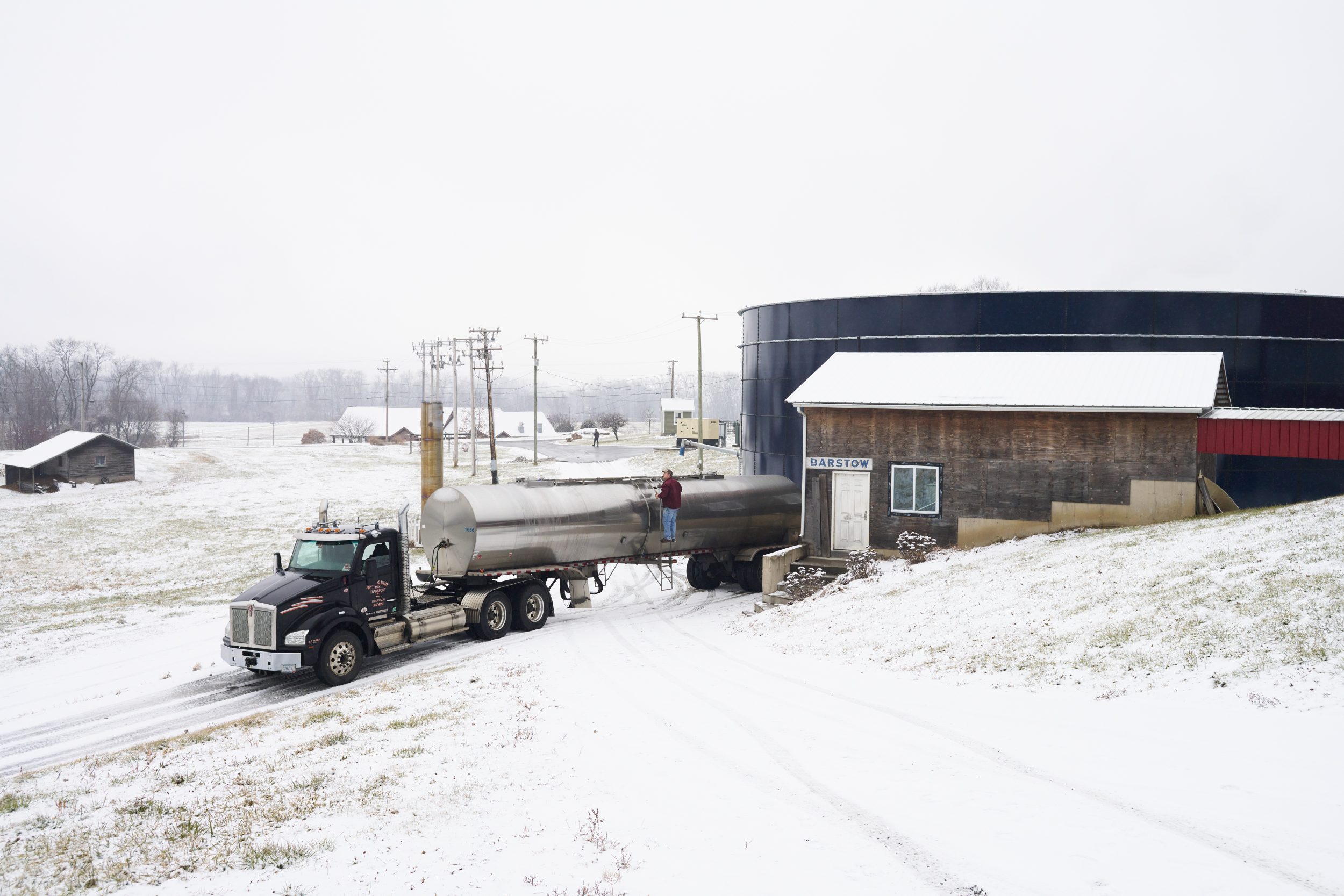 A milk truck fills up, while the large blue tank behind holds fertilizer that is produced
