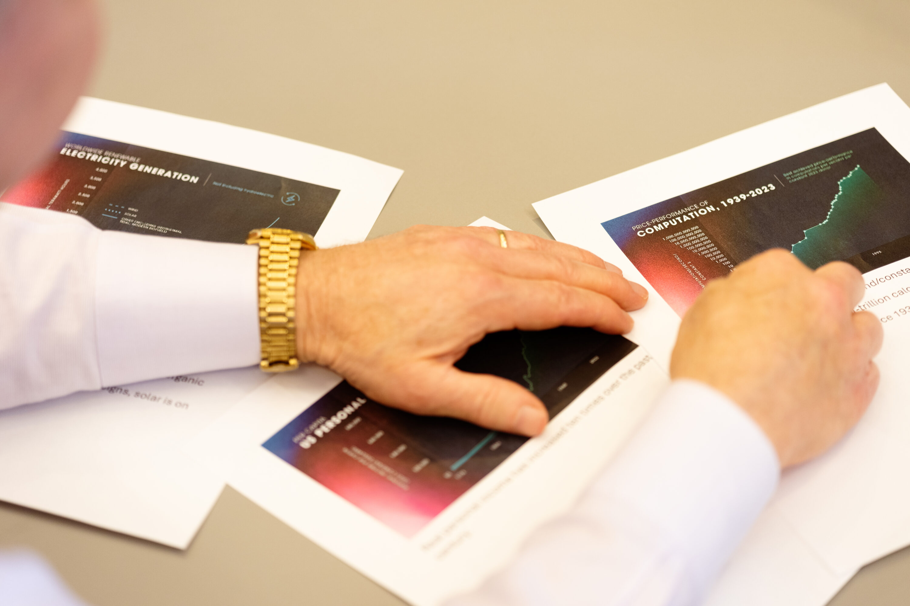 Ray Kurzweil points to printed charts spread across the interview table.