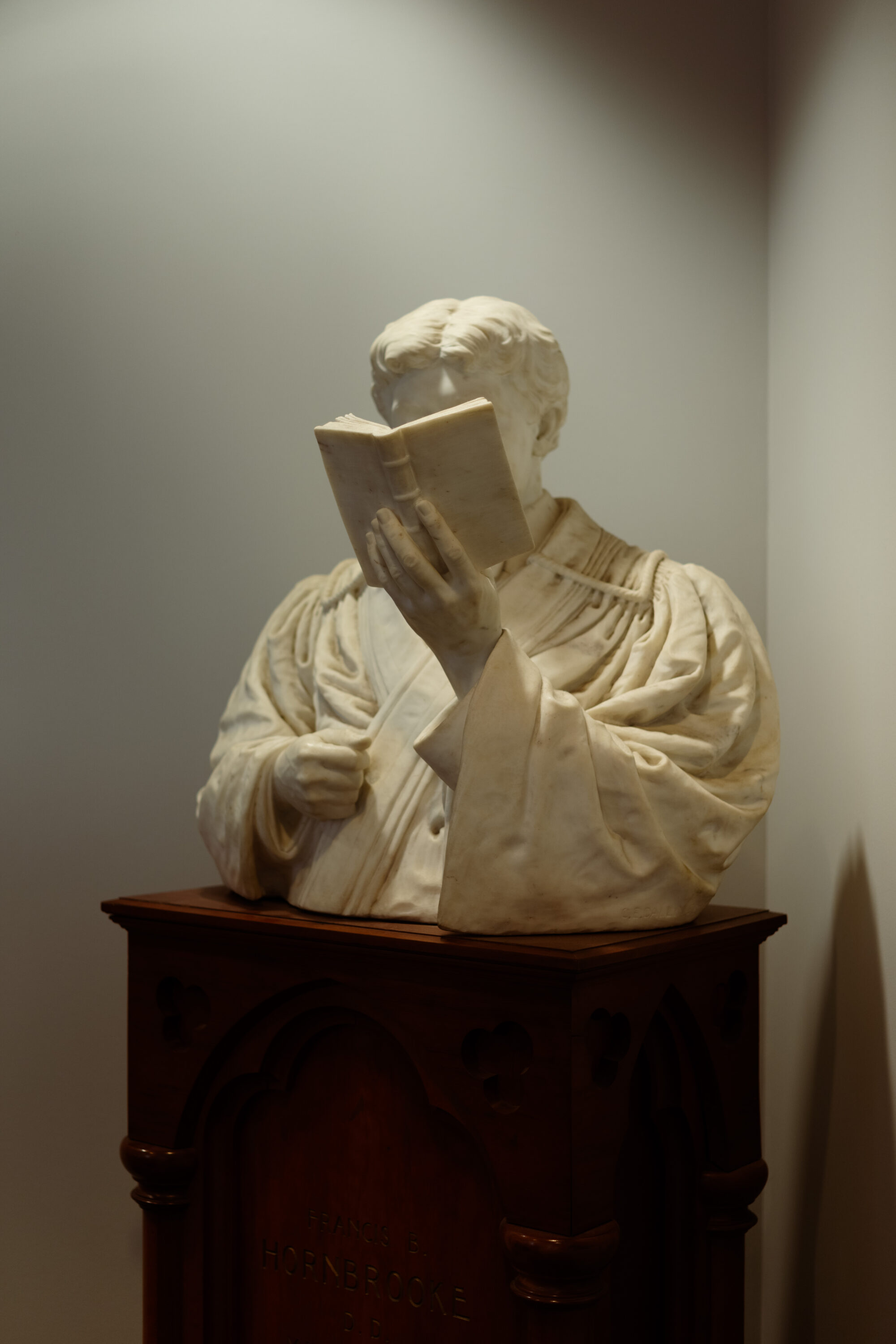 A sculpted bust holding an open book in the library.
