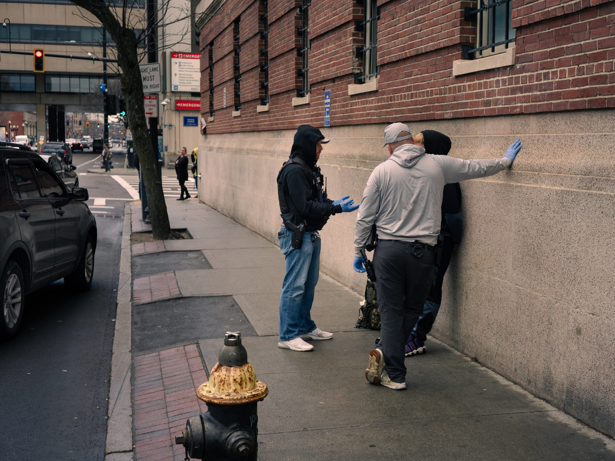 Police officers stop and question a man on Massachusetts Avenue near Mass and Cass in Boston Plainclothes police officers wearing blue gloves stop and question a man against a wall on Massachusetts Avenue Plainclothes police officers wearing blue gloves stop and question a man against a wall on Massachusetts Avenue