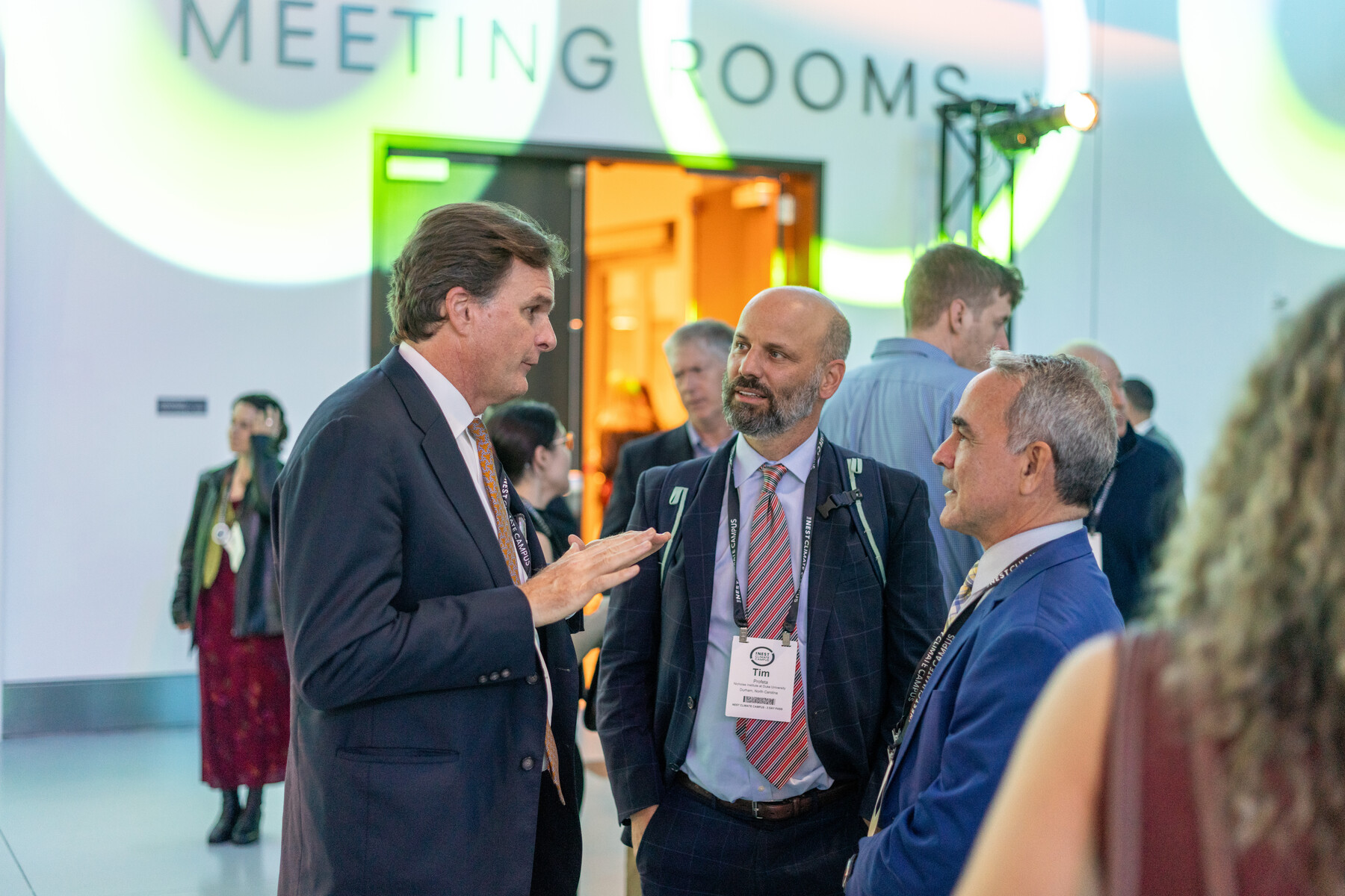 Three attendees talk in a reception space.