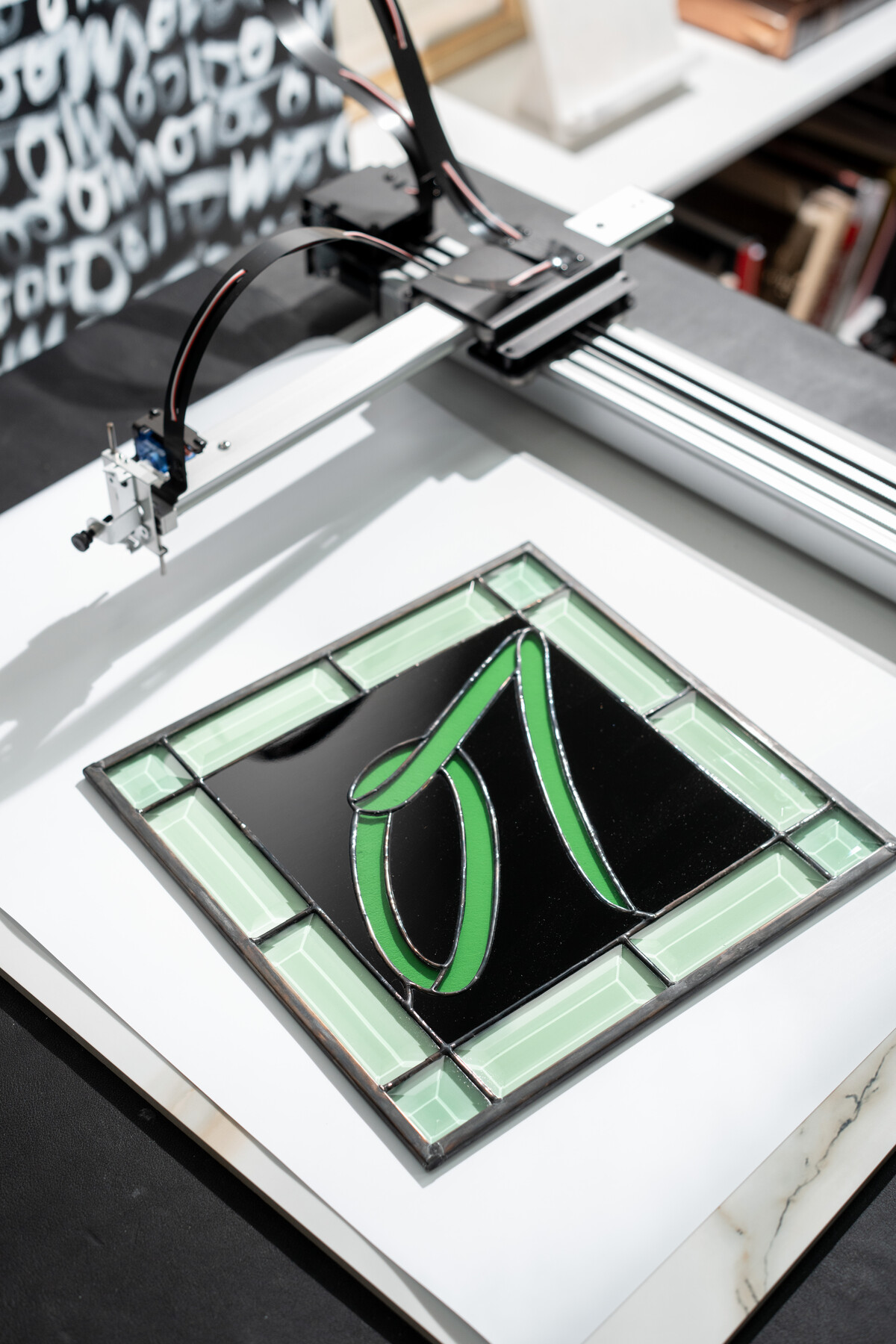 A green stained glass letterform rests beneath a machine in Stiles’s studio.