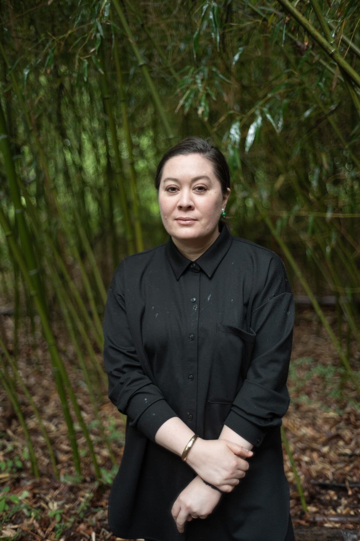 Sasha Stiles stands in black clothing among bamboo.
