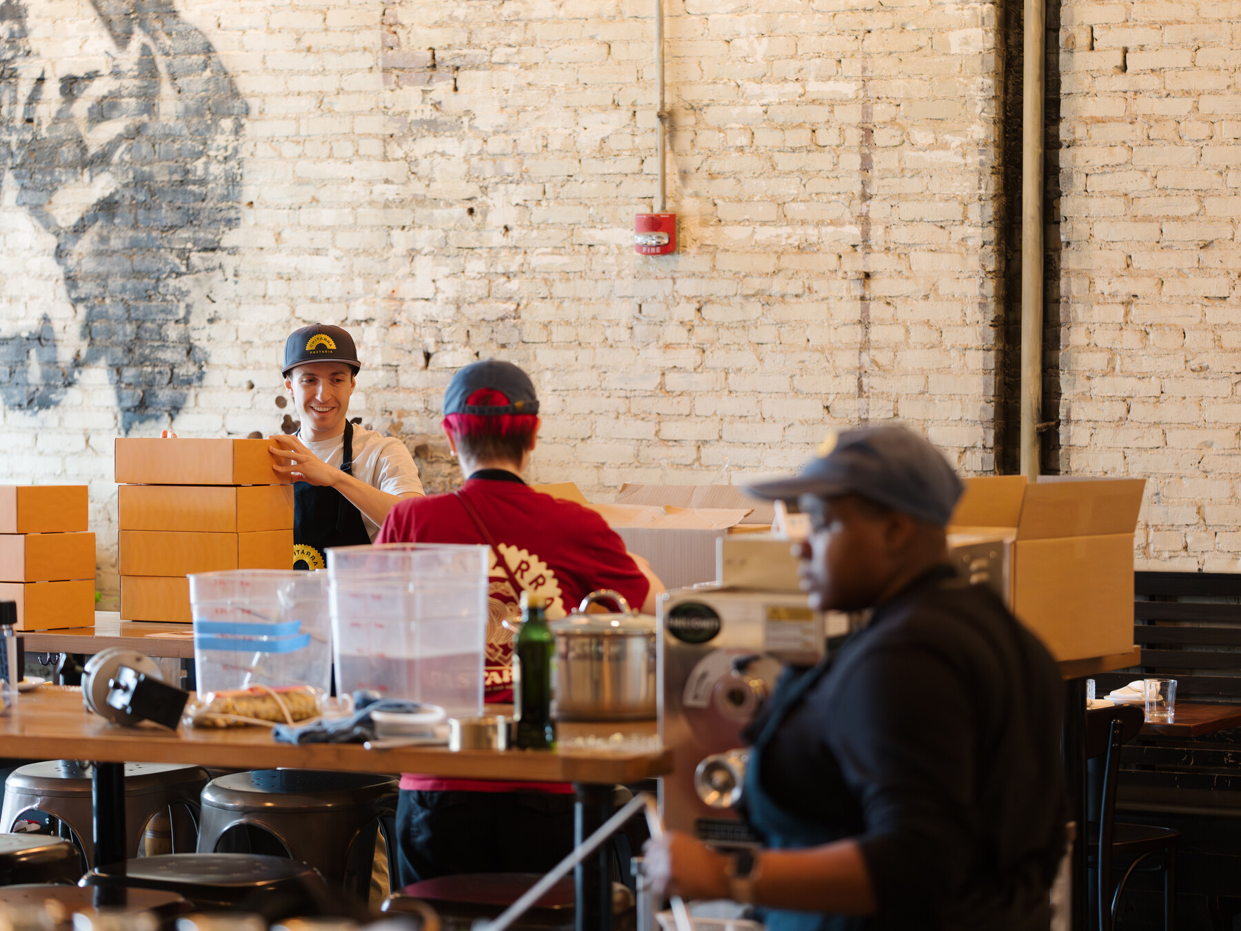 Stefano Micali stacks boxes as Julia Agostino and Ezra Kukis work nearby.