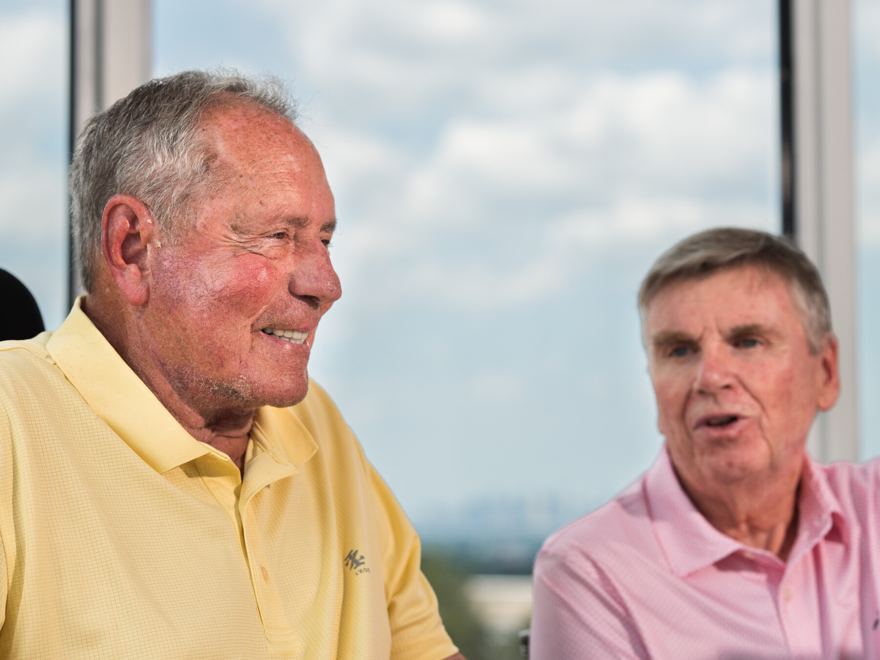 Bob Lobel smiles in the foreground while Mike Lynch speaks behind him.