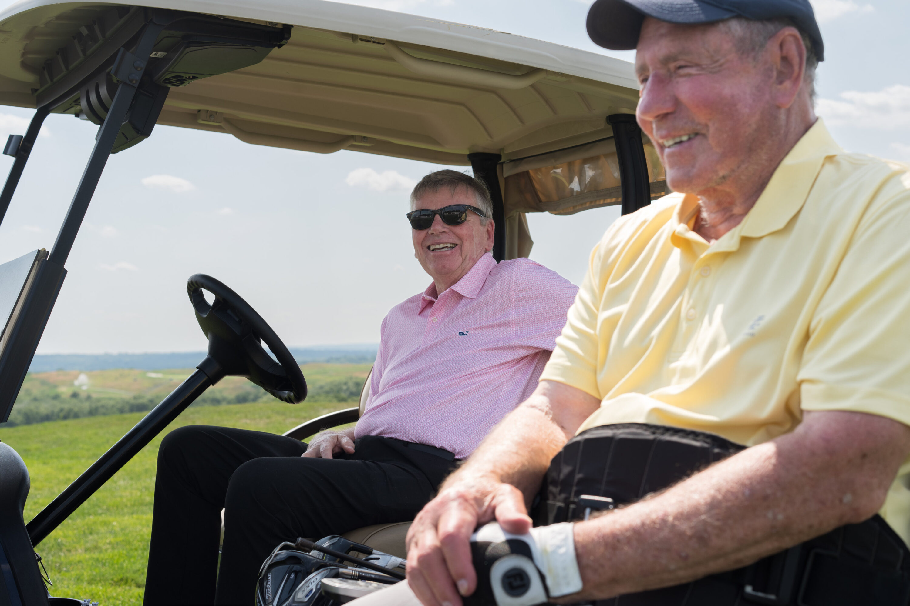 Mike Lynch smiles from a golf cart while Bob Lobel sits beside him at Granite Links.