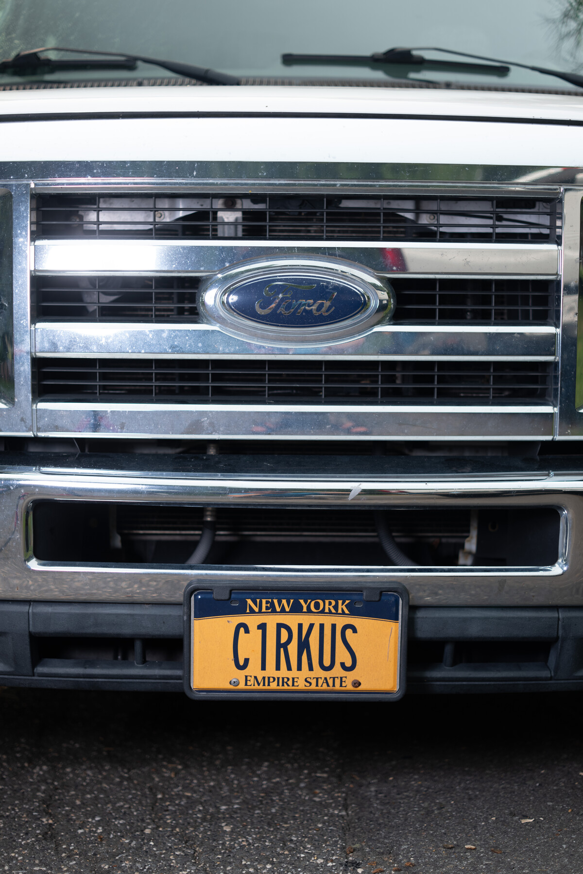 The front of a circus truck bears a New York C1RKUS license plate.