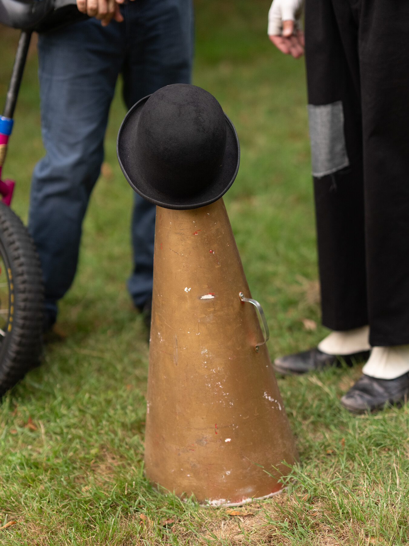 A black bowler hat rests on the narrow top of a tan cone.