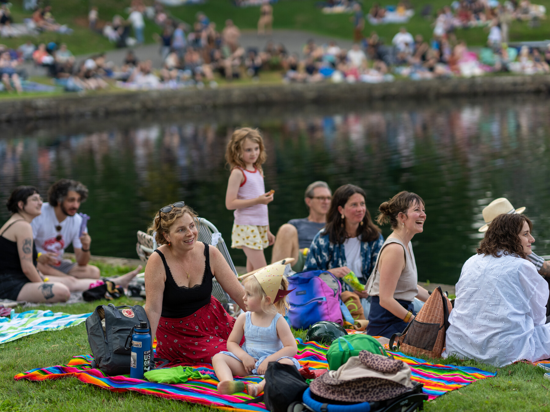 Families and other visitors sit beside Crescent Water watching the circus.