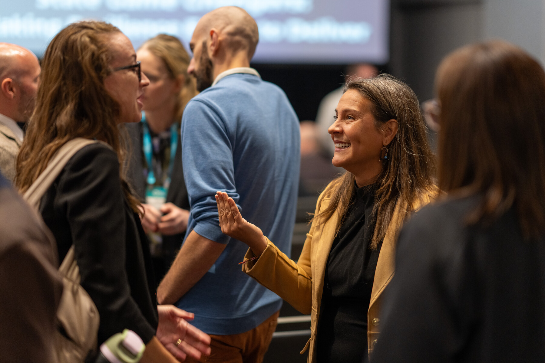 Small groups talk after a session; one woman gestures in the foreground.