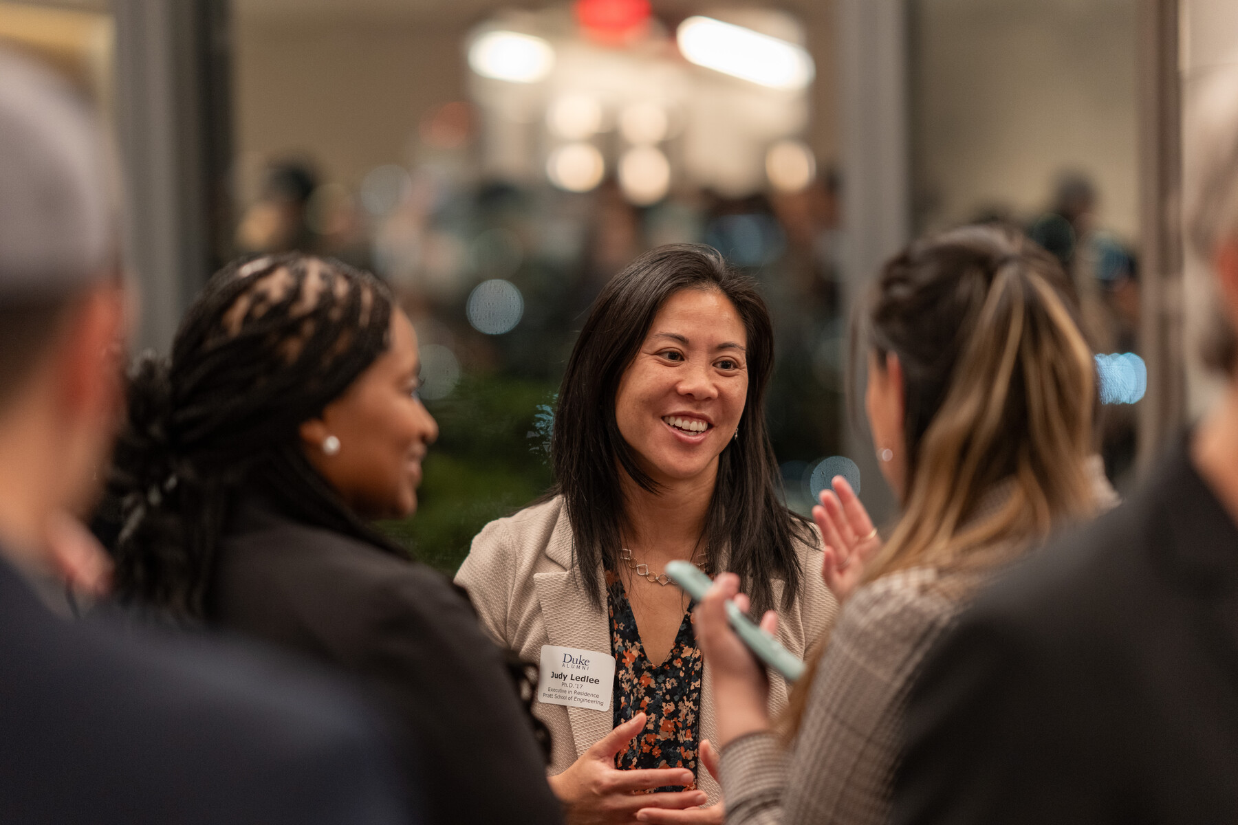 A woman speaks with other guests at an evening reception.