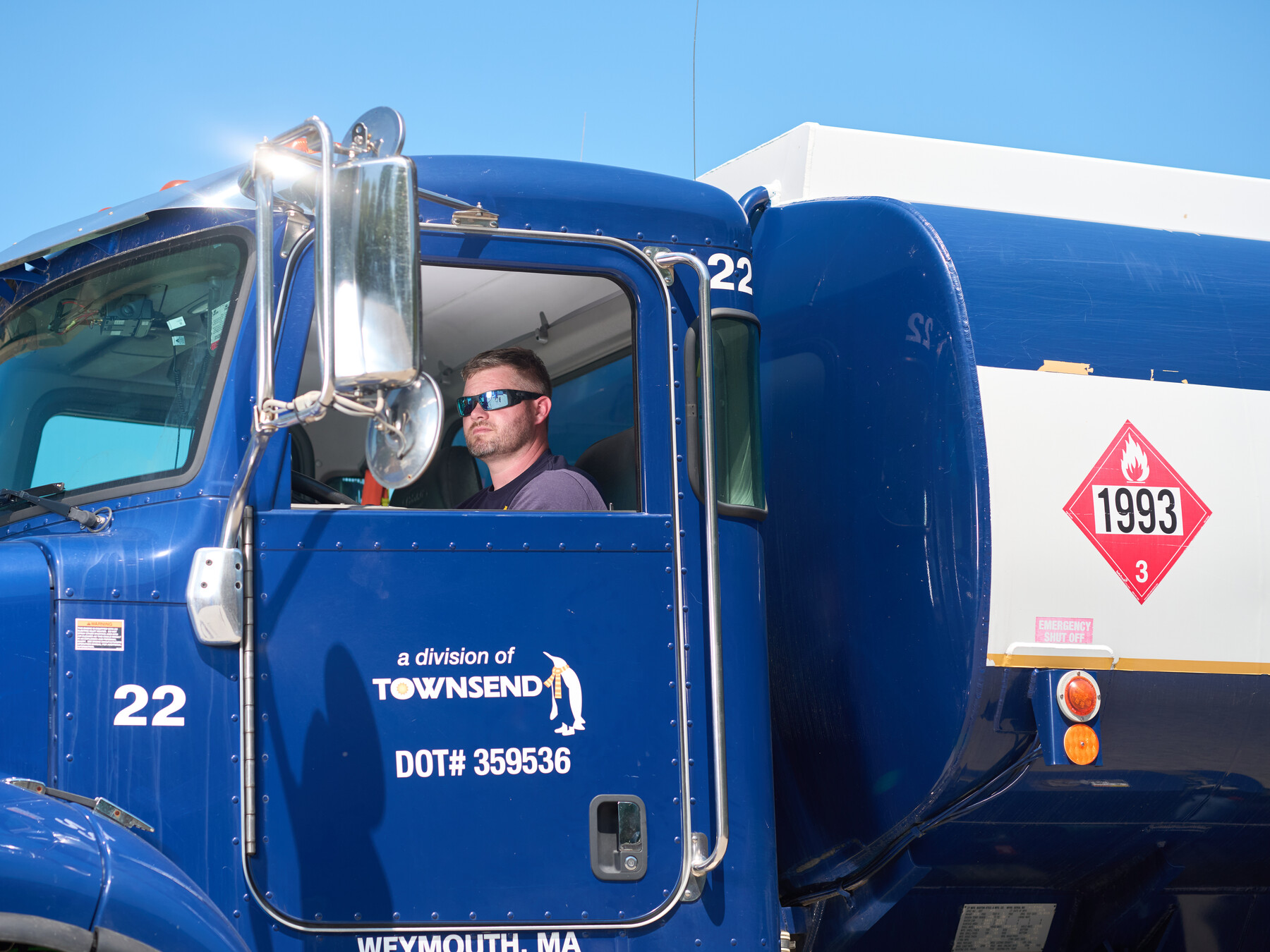 A man sits at the wheel of a blue fuel truck marked as a division of Townsend.