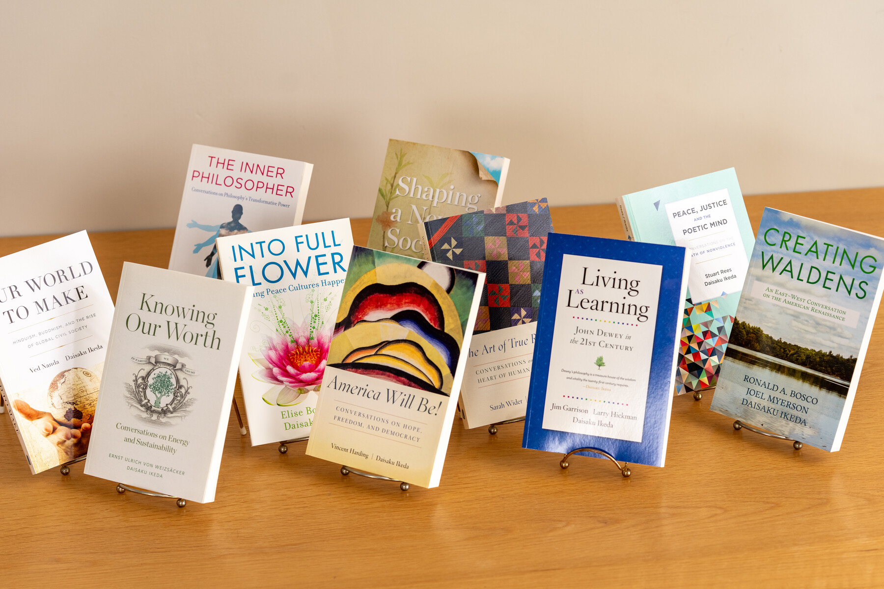 A group of books arranged upright on stands across a wooden table.