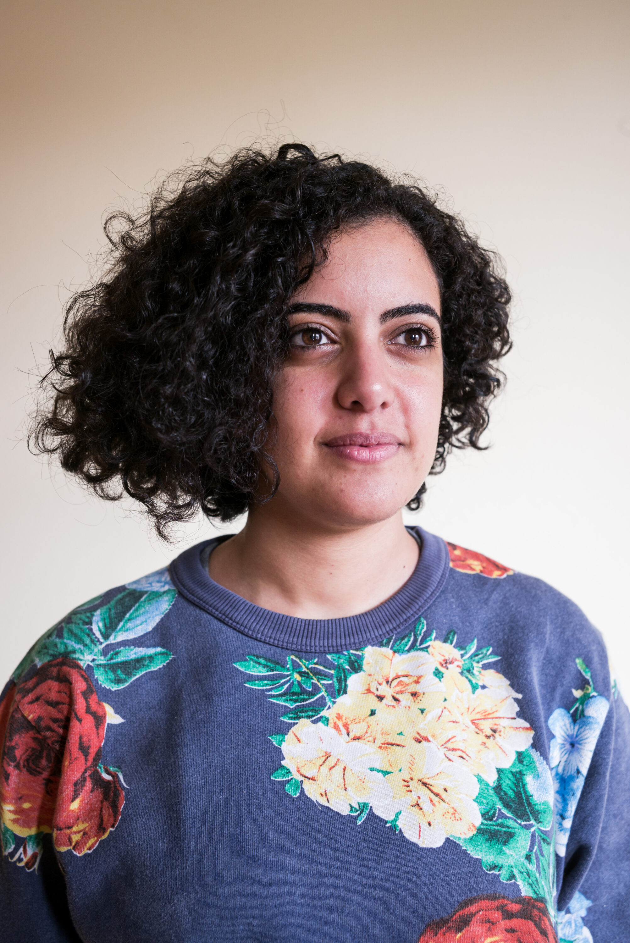 Heba Afify in a floral sweatshirt against a pale wall.