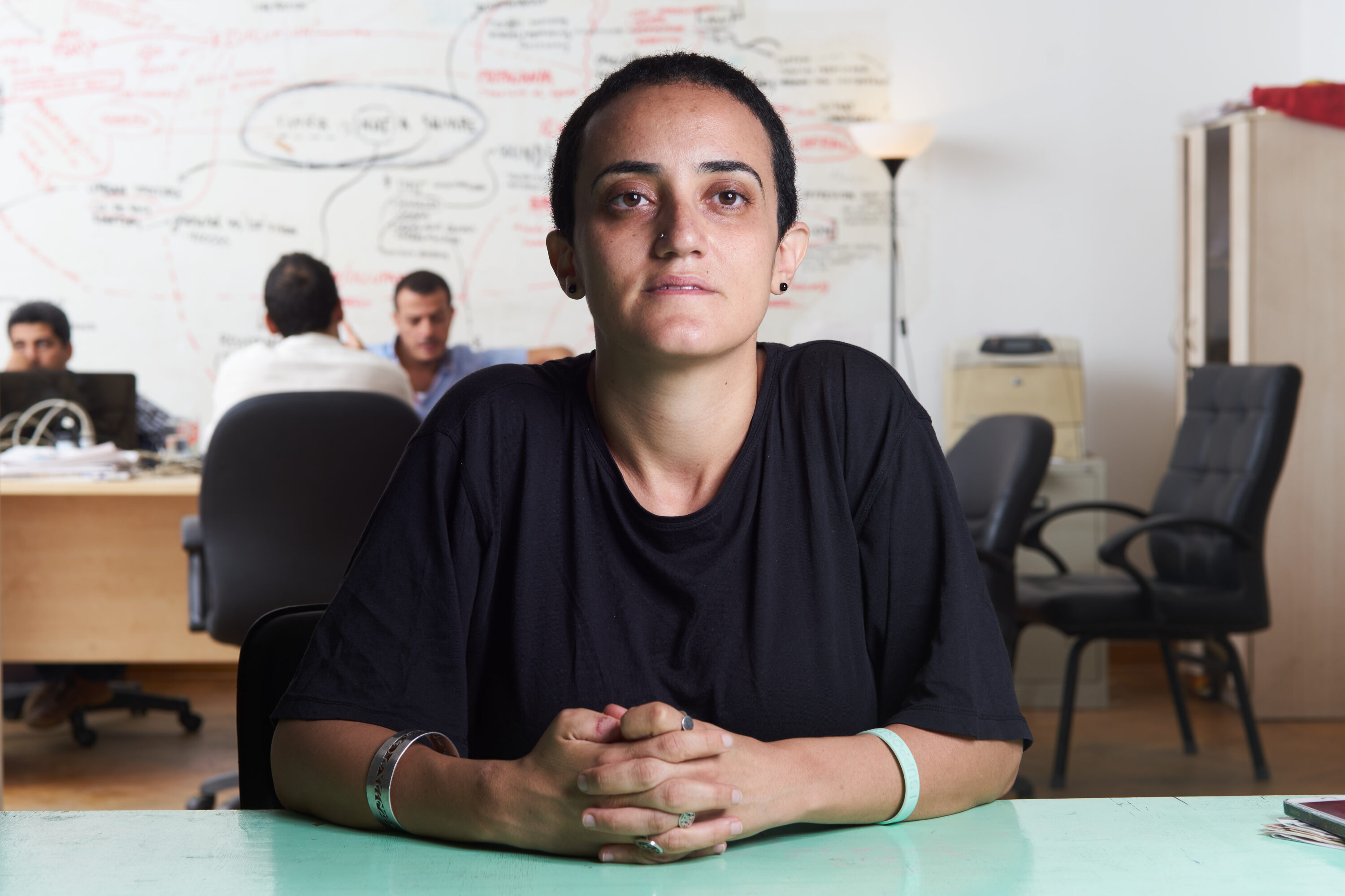Lina Attalah sits at a turquoise desk, with colleagues working behind her.